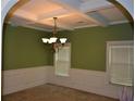 Elegant dining room showcasing coffered ceilings, wainscoting, and a stylish chandelier at 5896 Cliftondale Dr, Atlanta, GA 30349