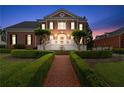 Elegant red brick home featuring manicured hedges and a brick path leading to the entrance at 5070 Riverlake Dr, Peachtree Corners, GA 30097