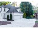 Side exterior elevation of home with three-car garage, well-manicured landscaping, and concrete driveway at 3258 Bransley Way, Duluth, GA 30097