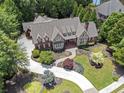 An aerial view showcases a brick and stone home on manicured lot with circular driveway and mature trees at 4634 Whitestone Way, Suwanee, GA 30024