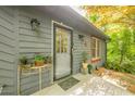 Close up of the front door and porch area featuring plants in containers and sconce lighting at 5848 Kingswood Ct, Norcross, GA 30093