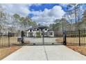View of a stately two-story home through a black iron security gate and concrete driveway at 4090 Sandy Lake Dr, Lithonia, GA 30038