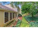 The backyard features large windows, a door, and extensive greenery, including a stone path and lush ground cover at 4477 Village Dr, Atlanta, GA 30338