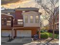 Rear exterior of a brick townhome featuring a garage, balcony, and cozy sunroom at 5210 Davenport Pl, Roswell, GA 30075