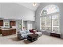 Open-concept living room with cathedral ceiling, arched window, and seamless flow to kitchen at 1613 Brolington Ct, Conyers, GA 30013
