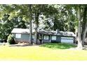 Classic single-story home featuring a welcoming front porch and attached garage, set amidst lush greenery at 205 Trickum Hills Ln, Woodstock, GA 30188