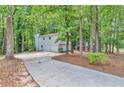 View of a home's garage and a winding driveway surrounded by lush trees and greenery at 5215 Mainstreet Park Dr, Stone Mountain, GA 30088