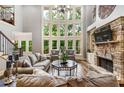 Sun-drenched living room with soaring ceilings, stone fireplace, hardwood floors, and floor-to-ceiling windows at 217 Fernwood Pl, Woodstock, GA 30188