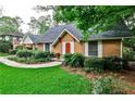 A cozy single-story brick house with a manicured lawn, mature trees, and a welcoming red front door at 1338 Talcott Pl, Decatur, GA 30033