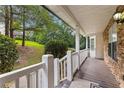 Inviting covered porch with stone accents, a wooden deck, and a view of the front yard and surrounding trees at 165 Lost Lake Trl, Villa Rica, GA 30180