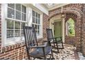 Charming brick front porch with rocking chairs, tile floor and arched entryway at 1718 Ridgewood Ne Dr, Atlanta, GA 30307