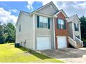 Side view of a two-story home featuring a two-car garage and vinyl siding, on a sunny day at 203 Galway Ln, Hampton, GA 30228