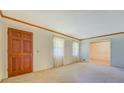 Bright living room features neutral carpet, natural wood trim, and a wooden front door at 1830 Francis Sw Rd, Conyers, GA 30094