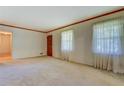 Neutral living room with light carpet, windows with lace curtains, and a wooden door at 1830 Francis Sw Rd, Conyers, GA 30094