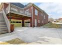 Rear view of brick home featuring lower garage access, upper deck, and yard at 2324 Blackberry Ct, Snellville, GA 30078