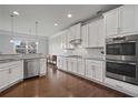 Modern white kitchen featuring stainless steel appliances, granite countertops, and ample cabinet space at 2050 Poplar Ridge Pl, Cumming, GA 30040
