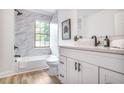 Modern bathroom features white cabinets, marble tile, and a shower-tub combo at 911 Oakland Sw Dr, Atlanta, GA 30310