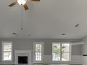 Cozy living room with bright white fireplace, ceiling fan, and abundant light from the backyard windows at 2420 Walnut Grove Way, Suwanee, GA 30024
