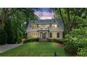 Charming two-story home featuring a manicured lawn and mature trees with the house lit at night, second story balcony at 2697 N Thompson Ne Rd, Atlanta, GA 30319