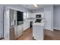 Modern kitchen with stainless steel refrigerator, white cabinets, island, and wood flooring at 5381 Briar Creek Ln, Norcross, GA 30071