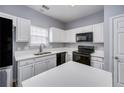 Well-lit kitchen featuring white cabinetry, black appliances, and a functional island at 5381 Briar Creek Ln, Norcross, GA 30071
