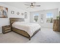 Bright main bedroom with neutral carpeting, three windows, a wood headboard, and decorative art at 7814 Messina Ct, Lithia Springs, GA 30122