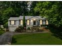 Charming home featuring a well-manicured front lawn and lush landscaping with mature trees and a driveway at 747 Channing Nw Dr, Atlanta, GA 30318