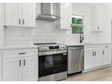 Modern kitchen featuring stainless steel appliances, white cabinets, and a stylish range hood at 3013 Michael Sw Dr, Marietta, GA 30060