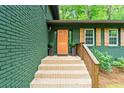 Close up of the home's front porch, featuring a wooden door and brick steps with wooden railing at 3597 Embry Cir, Atlanta, GA 30341