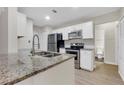 Modern kitchen with granite countertops, white cabinets, stainless steel appliances and stainless steel sink at 404 Hawkstone Way, Alpharetta, GA 30022