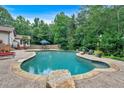 A backyard pool features stone coping and a surrounding patio for outdoor enjoyment at 3656 Ebenezer Rd, Marietta, GA 30066