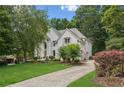 Charming two-story home with lush landscaping, mature trees, and an American flag waving in the breeze at 7235 Compton Cir, Cumming, GA 30040