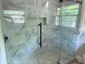 Glass shower featuring light marble tiling, a black showerhead, and a shower shelf at 1968 Rosewood Rd, Decatur, GA 30032