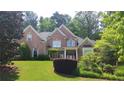 Brick two-story home featuring mature trees, green lawn, and classic architectural details at 2883 Thurleston Ln, Duluth, GA 30097