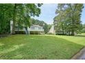 View of exterior and yard surrounded by mature trees and greenery for beautiful and serene setting at 6223 Emerald Springs Se Dr, Acworth, GA 30102