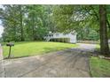 View of exterior and cracked driveway surrounded by mature trees and greenery with mailbox number at 6223 Emerald Springs Se Dr, Acworth, GA 30102
