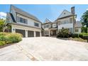 View of the home's white facade, grey shutters, stone accents, and three-car garage with an extra large driveway at 4559 Paradise Shoals Se Rd, Atlanta, GA 30339