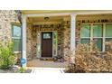 Inviting front porch with brick columns, a dark wood door, and manicured shrubs at 5381 Front Runner Ct, Sugar Hill, GA 30518