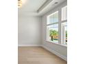 Bright bedroom featuring tray ceilings, hardwood floors, and large windows providing a beautiful view at 900 Melody Ridge Ln, Buford, GA 30518
