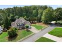 Aerial view of a well-manicured grey brick home with mature trees, green lawn and long driveway at 1254 Hadaway Garden Nw Dr, Kennesaw, GA 30152