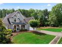 Charming grey brick home on a lush green lawn with mature trees and an inviting driveway at 1254 Hadaway Garden Nw Dr, Kennesaw, GA 30152