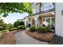 Inviting front porch with chairs, manicured landscaping and grey brick exterior at 1254 Hadaway Garden Nw Dr, Kennesaw, GA 30152