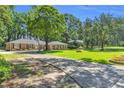Expansive front yard with mature trees, brick home, and basketball hoop on driveway at 400 Little John Nw Dr, Lilburn, GA 30047