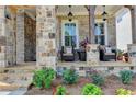Inviting front porch featuring stone pillars, a seating area, and well-maintained landscaping at 11255 Knollwood Bnd, Johns Creek, GA 30097