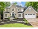 Charming two-story home with a manicured lawn, dark mulch flower beds, and stone walkway at 910 Kings Arms Way, Johns Creek, GA 30022