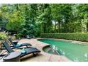 Private in-ground pool surrounded by lush landscaping and lounge chairs on a stone patio at 910 Kings Arms Way, Johns Creek, GA 30022