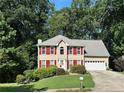 Inviting two-story home with red shutters, lush greenery, and a convenient attached garage at 1019 Wolf Springs Ct, Lawrenceville, GA 30043