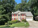 Charming two-story home featuring a well-manicured lawn, bright red shutters, and an attached two-car garage at 1019 Wolf Springs Ct, Lawrenceville, GA 30043