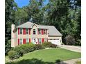 Charming two-story home featuring a well-manicured lawn, bright red shutters, and an attached two-car garage at 1019 Wolf Springs Ct, Lawrenceville, GA 30043