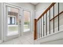 Bright entryway with white tile floors, a staircase with wood and black railings, and a glass door at 5933 Brookside Oak Cir, Norcross, GA 30093